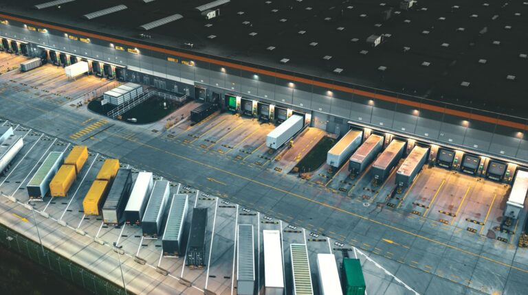 Global contract logistics market to hit €372.6bn by 2030, Ti Insight forecasts Top view of many trailers and containers near the logistics warehouse, in the evening.