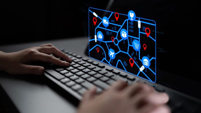 A person types at a keyboard with logistics mapping on a screen in front of them.