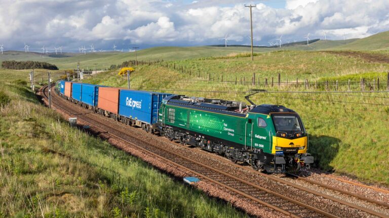 A green GoExpress-branded train pulls container carriages along a railway track.