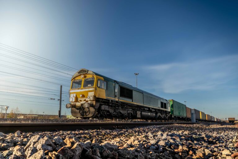 Profile view of a goods train with Intermodal wagons full of shipping container boxes for import and export in a yard or sidings